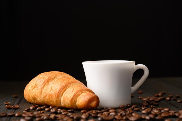 Croissants con café y granos de café sobre un fondo de madera