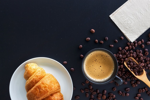 Croissants calientes de café, frijoles y mantequilla en la mesa negra