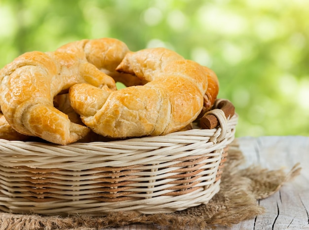 Croissants en una cesta de mimbre sobre un fondo de madera