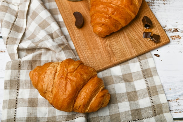 Croissants de chocolate. El comienzo de la mañana. Una taza de café. Croissant francés fresco. Taza de café y cruasanes recién horneados sobre un fondo de madera. Vista desde arriba.