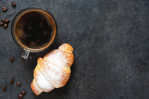 Croissants com café expresso em um fundo preto de concreto. vista de cima.