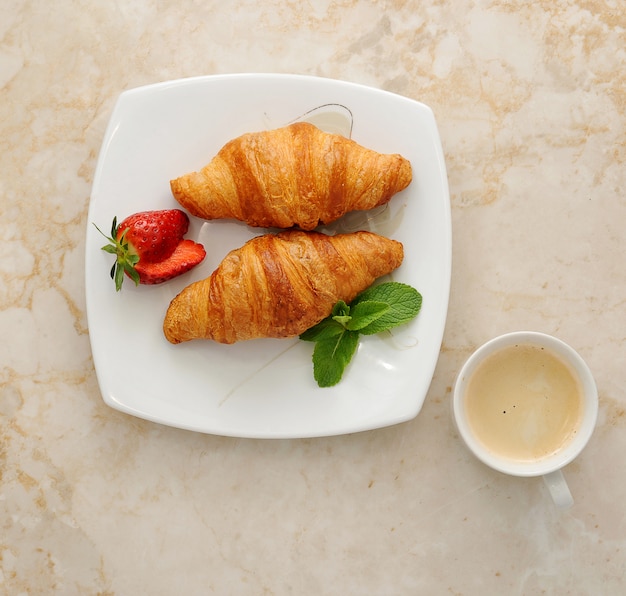 Croissants com café, morangos e folhas de hortelã