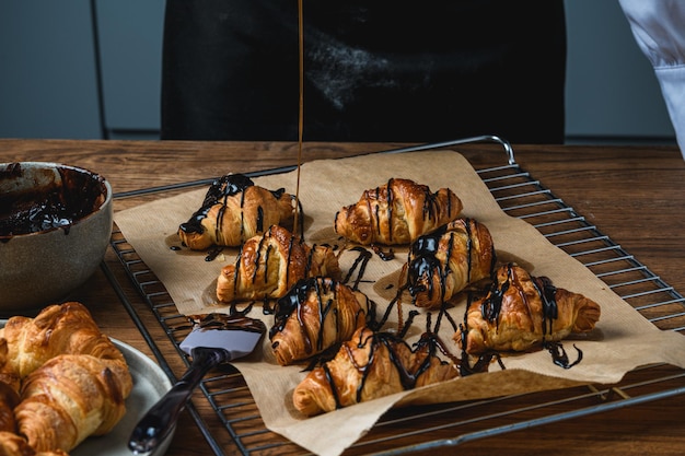 Croissants com chocolate e granulado sobre uma mesa de madeira.