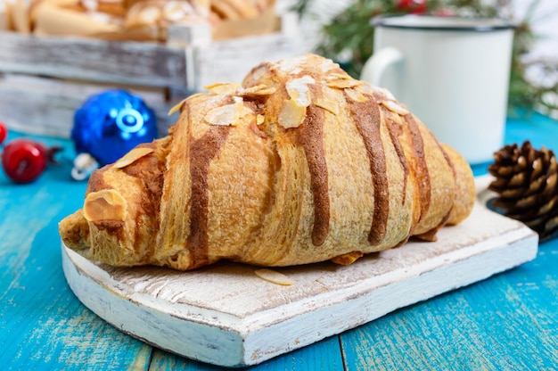 Croissants com flocos de amêndoa, caneca de café em um fundo azul de madeira. Café da manhã. Pastelaria francesa tradicional.