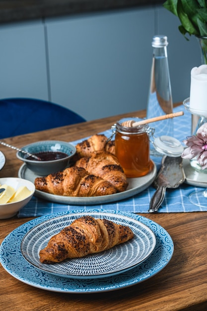 Croissants com geléia e mel em uma mesa de madeira.