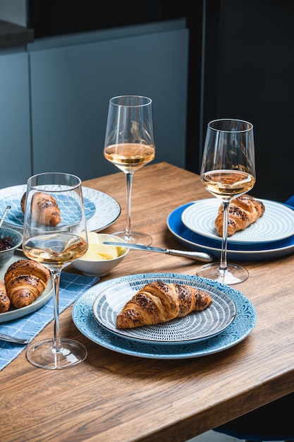 Croissants com manteiga e vinho em uma mesa de madeira.