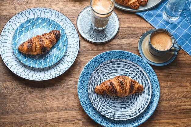 Croissants com uma xícara de café em uma mesa de madeira.