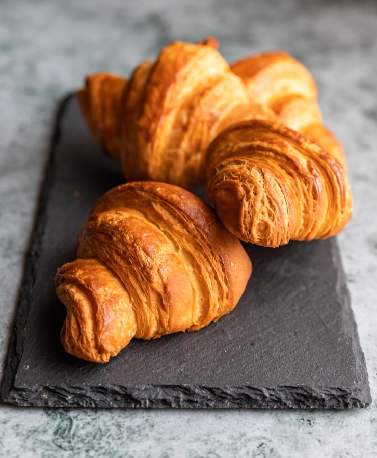 Foto croissants crocantes saborosos no fundo cinza da placa de pedra preta padaria caseira para o café da manhã