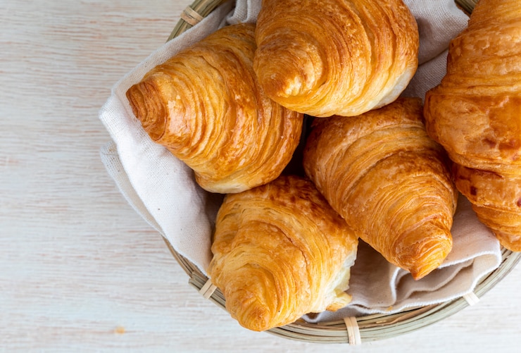 Foto croissants de manteiga na cesta de vime pequena. vista do topo