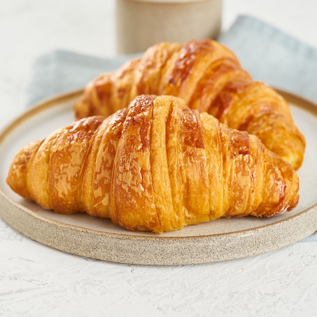 croissants deliciosos no prato e bebida quente na caneca. Café da manhã francês com bolos frescos