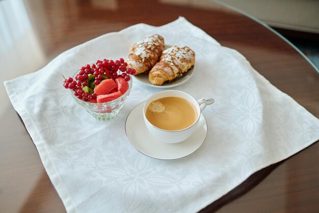 Croissants der frischen Beerenwüste zwei und Tasse Kaffee auf weißer Serviette