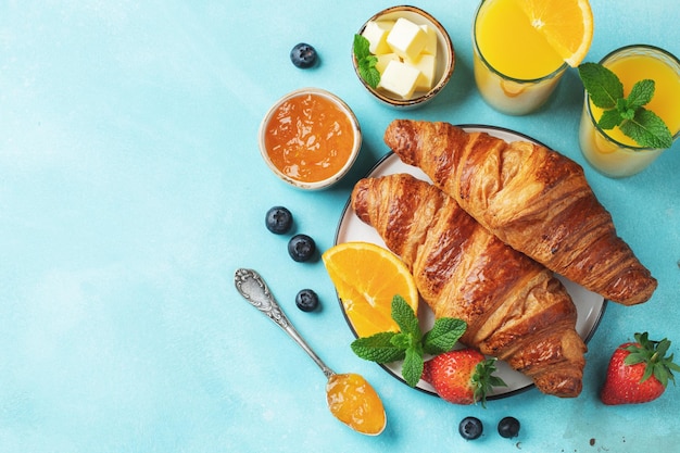 Croissants doces frescos com manteiga e geléia de laranja no café da manhã café da manhã continental em uma mesa de concreto brilhante vista superior com espaço de cópia