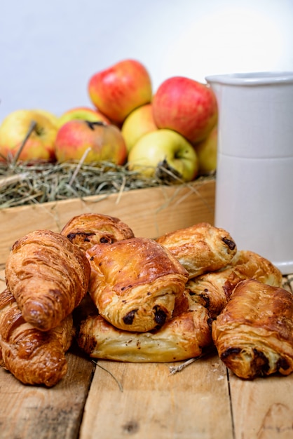 Croissants y dolores al chocolate con una caja de manzanas