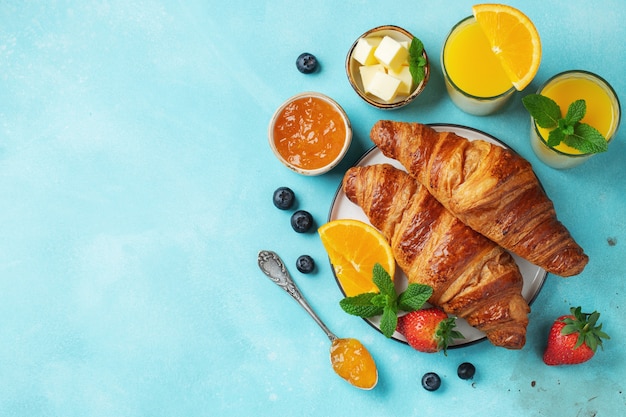 Croissants dulces recién hechos con mantequilla y mermelada de naranja para el desayuno.