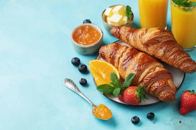 Croissants dulces recién hechos con mantequilla y mermelada de naranja para el desayuno.