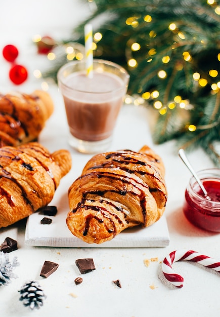 Croissants e bebida de cacau em mesa branca decorada com decoração de natal