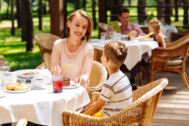 Croissants e chá. mãe carinhosa e sorridente, sentindo-se inacreditável enquanto trata seu filho com croissants e chá