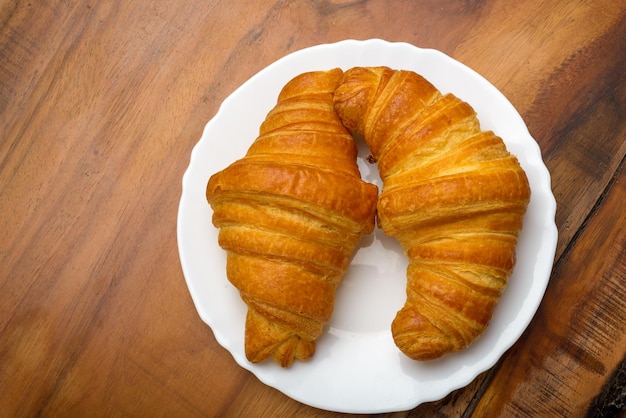 Croissants em chapa branca na mesa de madeira Vista superior