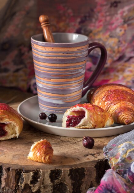 Croissants em um prato com frutas e uma xícara de café