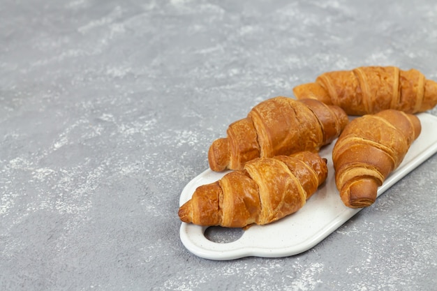 Croissants franceses frescos em uma placa de cerâmica na mesa de pedra cinza