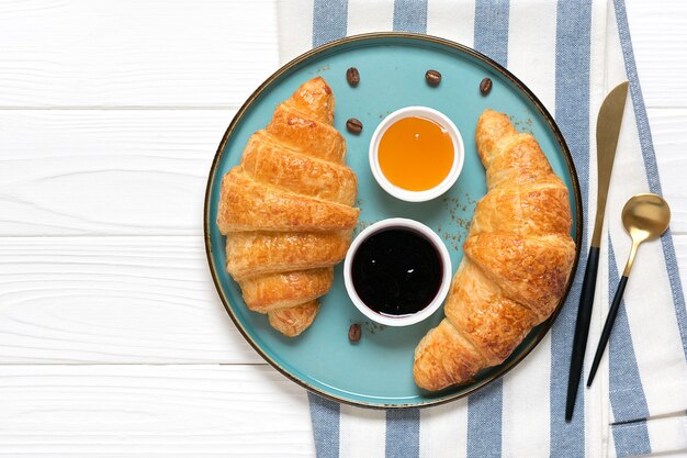 Croissants franceses frescos con mermelada de arándanos, miel y taza de café