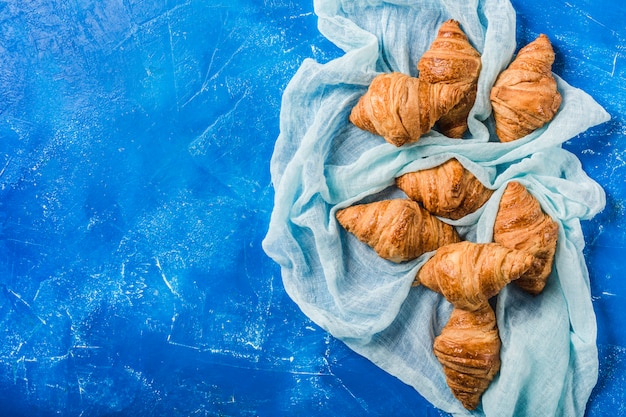 Croissants franceses recién horneados con una clásica mesa azul con una servilleta turquesa.