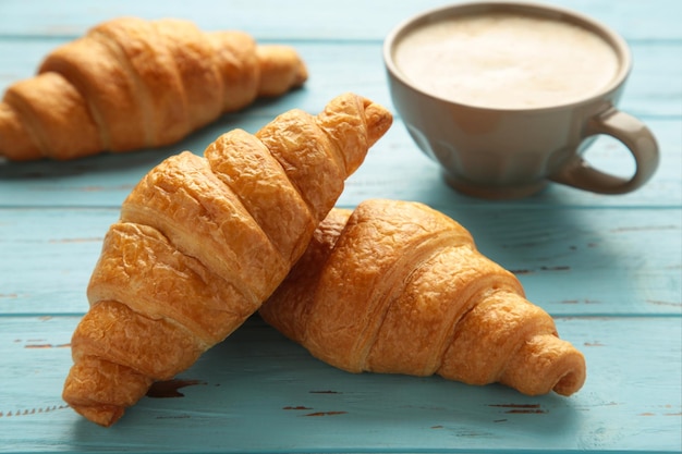 Croissants franceses y taza de café sobre fondo de madera azul