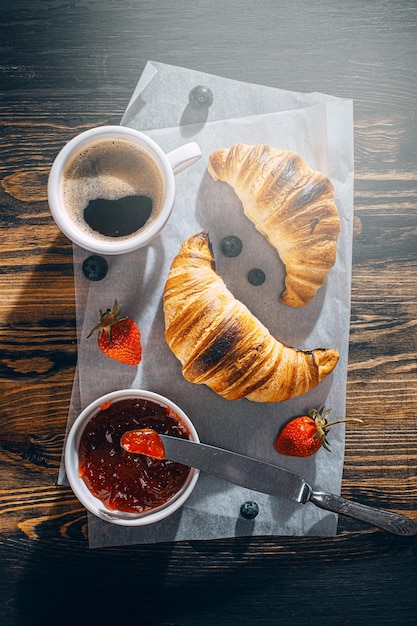 Croissants frescos apenas assados com geléia e café na mesa ao sol da manhã delicioso conceito de café da manhã