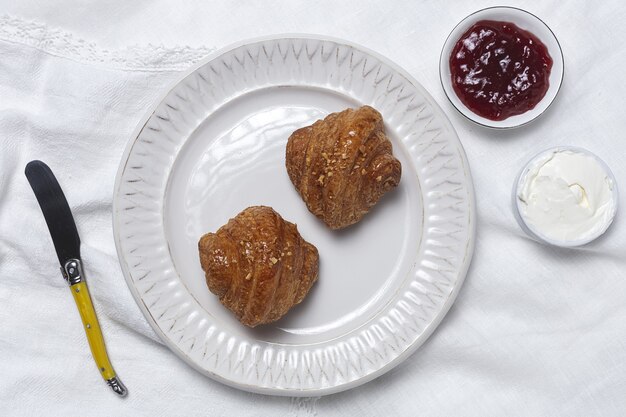 Croissants frescos caseiros franceses na mesa branca com geleia e manteiga