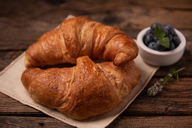 Croissants frescos caseiros na mesa de madeira fecham