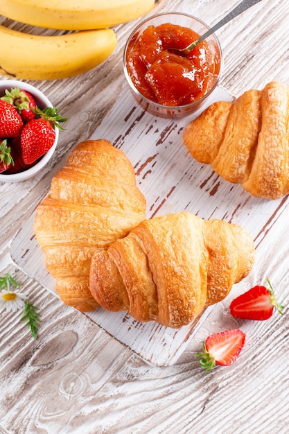 Croissants frescos com geleia no café da manhã na mesa de madeira