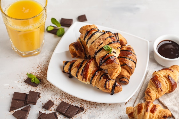 Croissants frescos de café da manhã com calda de chocolate e suco de laranja. Conceito de sobremesa de cozinha francesa.