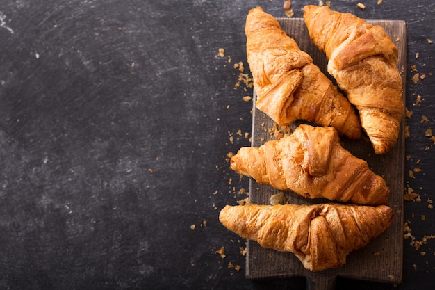 Croissants frescos em uma placa de madeira, vista superior