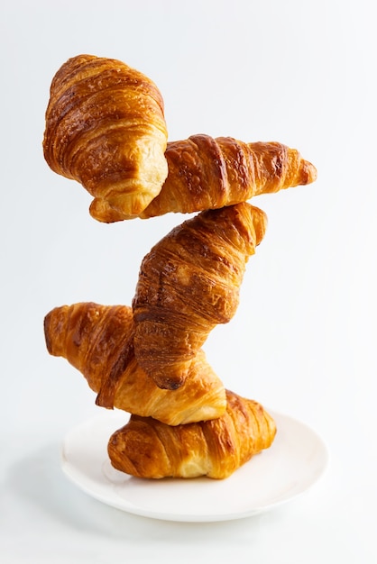 Croissants frescos en equilibrio sobre una placa blanca aislada