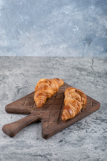 Croissants frescos y sabrosos colocados sobre una tabla de cortar de madera.