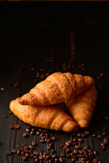 Croissants con granos de café sobre un fondo de madera