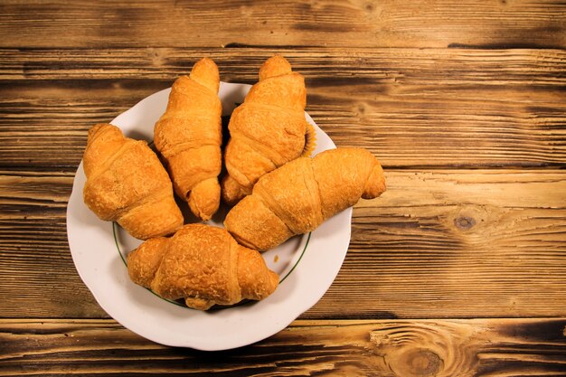 Croissants in der Platte auf Holztisch. Ansicht von oben