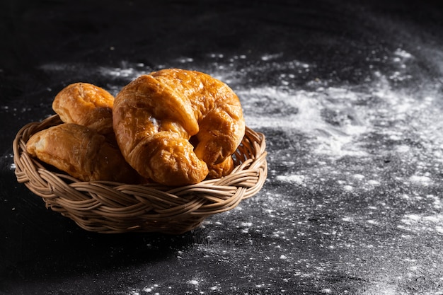 Croissants in einem Weidenkorb auf einem schwarzen Boden