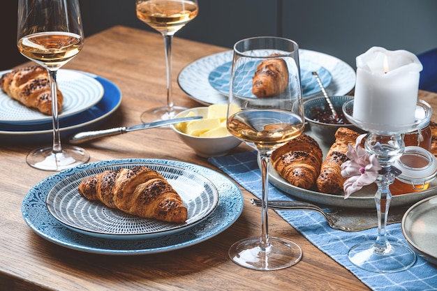 Croissants con mantequilla y vino en una mesa de madera.