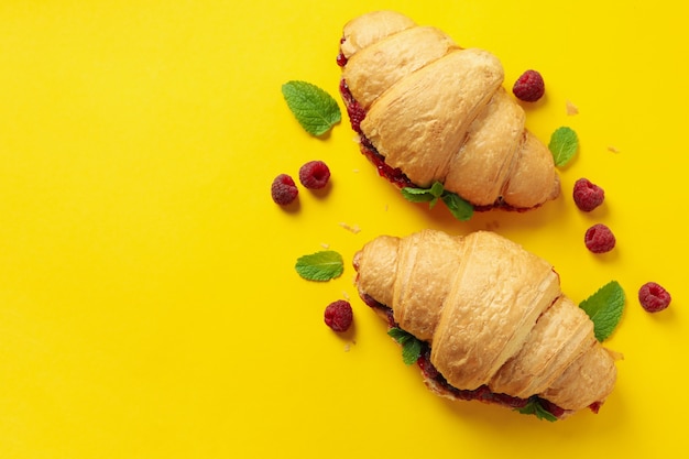 Croissants con mermelada de frambuesa sobre fondo amarillo