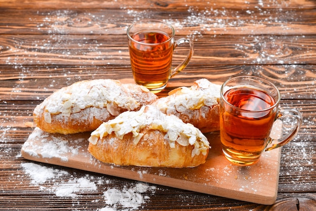 Croissants mit Mandeln und Tee auf einem Holztisch.