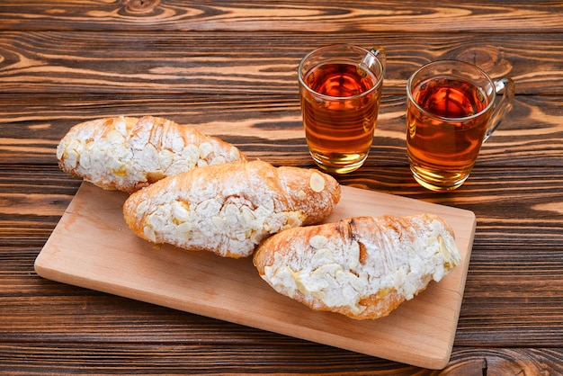 Croissants mit Mandeln und Tee auf einem Holztisch