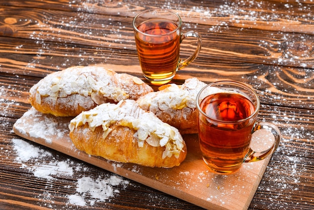 Croissants mit Mandeln und Tee auf einem Holztisch