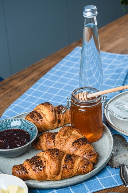 Croissants mit Marmelade und Honig auf einem Holztisch.