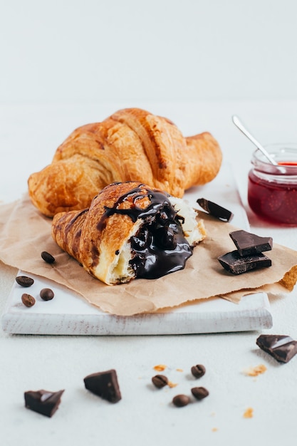 Croissants mit Schokoladenfüllung und Erdbeermarmelade auf einer weißen Tischnahaufnahme