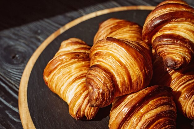 Croissants recém-assados. croissants de manteiga e pãezinhos perfumados em um suporte de pedra. pastelaria francesa e americana.