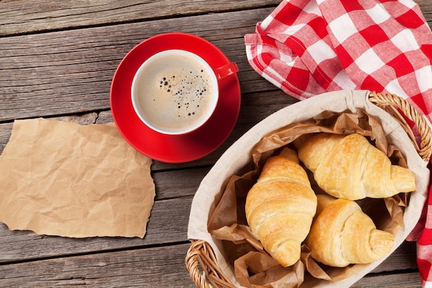 Croissants recién hechos y café en la mesa de madera