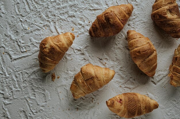 croissants recién hechos y suaves yacen sobre una mesa blanca de fondo de hormigón y pasteles