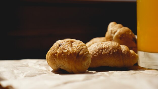 Croissants recién horneados con jugo de naranja sobre papel kraft. Fotografía de detalle de delicioso postre fresco para el desayuno.