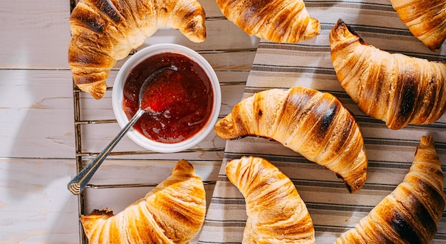 Croissants recién horneados con mermelada y café en la mesa al sol de la mañana delicioso concepto de desayuno